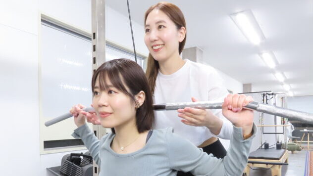 高田馬場・目白・下落合エリアのパーソナルジム『パーソナルランド』で、女性トレーナーがスクワットの正しいフォームを丁寧に指導している様子。初心者も安心して筋力トレーニングに取り組めるパーソナルサポート。